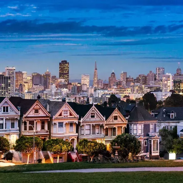 Las famosas Damas Pintadas de Alamo Square aparecen fotografiadas ante el horizonte de San Francisco al anochecer.